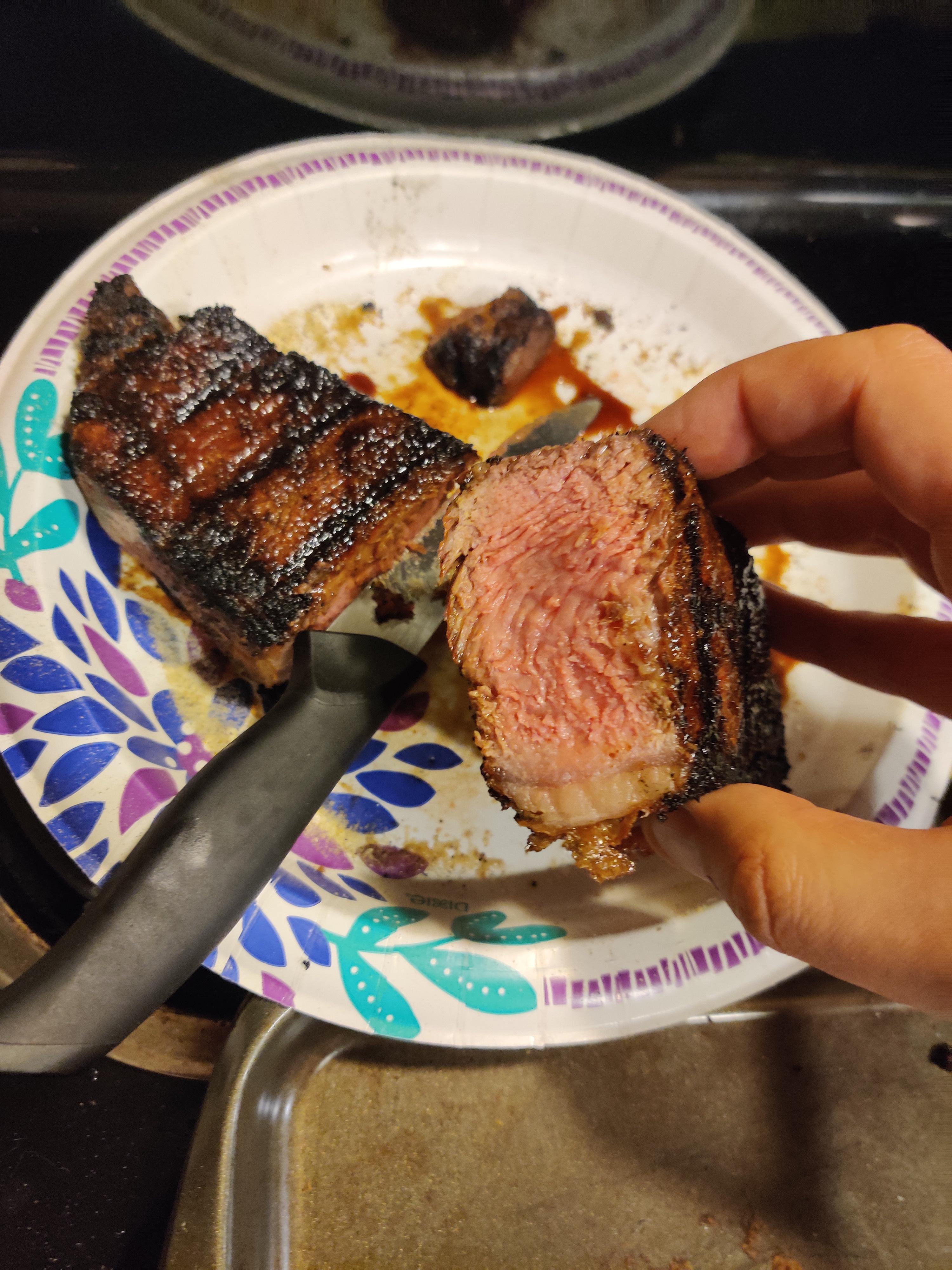 Medium Rare Prime New York Strip Steak on a charcoal grill. - Dining